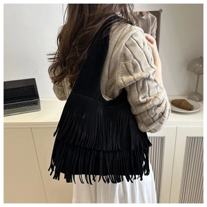 Detail of black faux suede tote bag featuring layered long tassels and bohemian fringe design