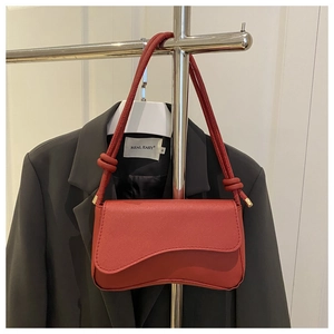 Detail der roten strukturierten Ledertasche mit Wellenklappe und geknotetem Schultergurt
