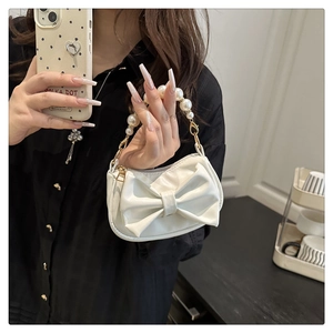 Close-up of white PU leather handbag with a large bow and pearl beaded handle