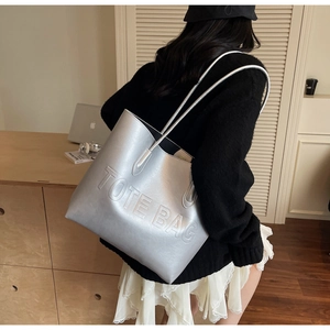 Detail of silver metallic tote bag featuring embossed logo and premium leather texture