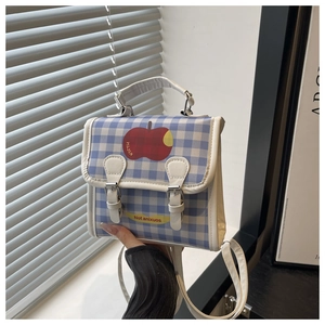 Close-up of blue checkered crossbody bag featuring a cute apple print and metal clasp