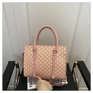 Detail view of pink tote bag with M-letter monogram texture and golden metal accents