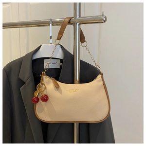 Detail of beige litchi grain shoulder bag with brown leather trim and cherry charm