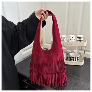 Detail of wine red suede bag featuring three layers of long tassels and knot handle