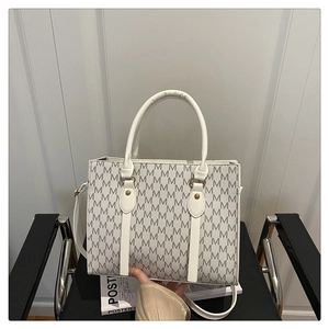 Detail of white tote bag with gray M-pattern texture on a black leather chair