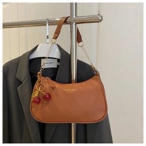 Detail of brown litchi pattern leather bag with gold chain and cherry charm