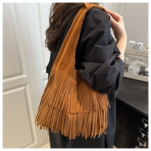 Detailed back view of a brown suede tote bag with long fringe tassels in a home setting