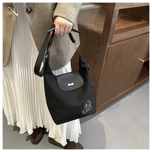 Detail of black canvas tote bag featuring silver bone buckle and cute cartoon dog print