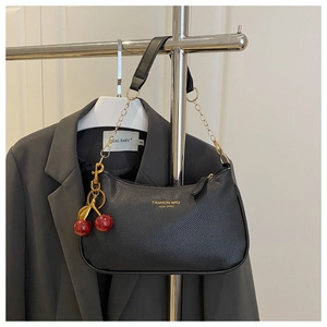Detail of black lychee grain hobo bag with gold chain strap and red cherry charm