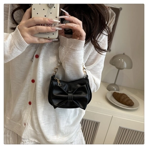 Detail of a black PU leather bag featuring a large bow and pearl chain handle