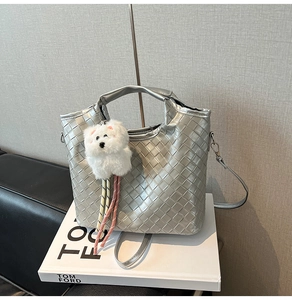 Detail of silver woven crossbody bag with diamond texture and plush puppy charm decor