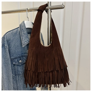 Macro view of dark brown suede shoulder bag featuring layered fringe tassels and texture
