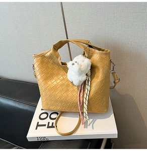 Detail of woven leather tote bag in ginger yellow with plush puppy charm and strap