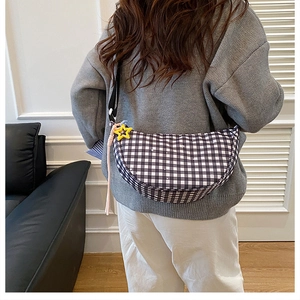 Detail of gingham moon bag with yellow star pendant and pink woven cord shown on model
