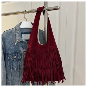 Detail of burgundy suede tote bag featuring layered long fringe and bohemian tassel accents