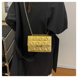 Detail of gold quilted chain bag with high-shine triangular texture worn by a model