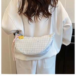 Detail of light blue checkered dumpling bag with star pendant on a white strap