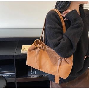 Detail view of brown suede tote bag featuring slim leather straps and metal buckle accent
