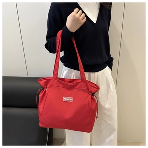 Detail of red nylon tote bag featuring side drawstrings and a white Fashion label
