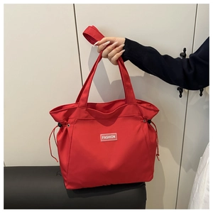 Detailed view of red nylon tote bag featuring Fashion label and adjustable side drawstrings