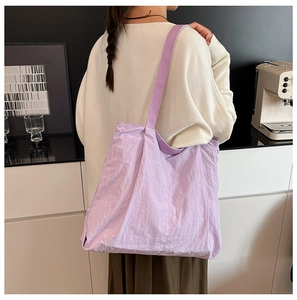 Close-up of light purple pleated tote bag with branded shoulder strap and large capacity