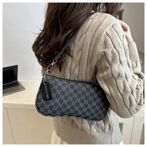 Detail of retro underarm bag with monogram pattern and fashion hangtag on knit sweater