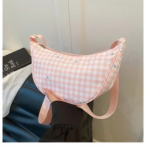 Detail of pink plaid crescent bag featuring star patterns and woven shoulder strap