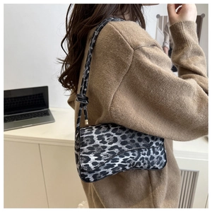 Detail shot of vintage leopard print saddle bag styled with a beige knit sweater