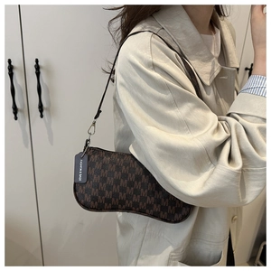 Detail of vintage brown baguette bag with M-letter jacquard and leather shoulder strap