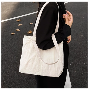 Close-up of a white tote bag featuring wrinkled texture fabric and double strap design