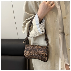 Detail of leopard print handbag showing smooth leather texture and gold-tipped straps