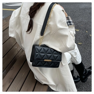 Classic black quilted crossbody bag with gold chain strap shown on a white shirt model