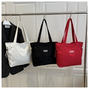 Detailed view of canvas tote bags in white, black, and red with drawstring sides