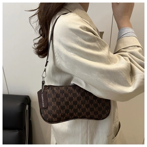 Detail of vintage moon-shaped shoulder bag with brown M-pattern print and fashion tag