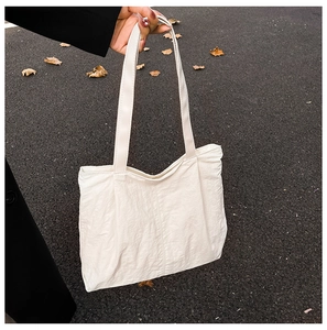 Close-up of off-white tote bag with textured fabric and straps for daily commuting