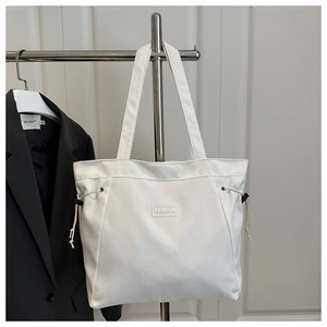 Detail of white nylon tote bag with Fashion patch and adjustable drawstring side