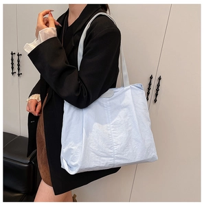 Side view of a light blue large capacity tote bag with stitching detail and shoulder straps