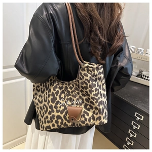 Close-up of leopard print canvas tote bag with brown leather strap worn by a model