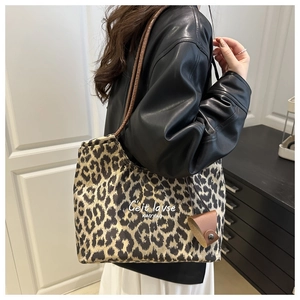 Detail of leopard print tote bag featuring C'est lavse text and brown leather straps