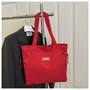 Detail of red nylon tote bag featuring fashion label and side adjustable drawstrings