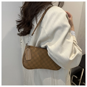 Detail of a brown crescent bag with M-pattern texture and a chic fashion leather tag