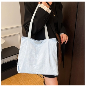 Close-up of light blue wrinkled fabric tote bag with rectangular MY COCO logo patch