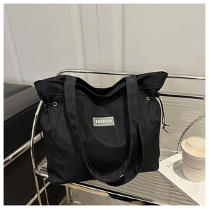 Detail of black nylon tote bag with Fashion label and adjustable drawstring design