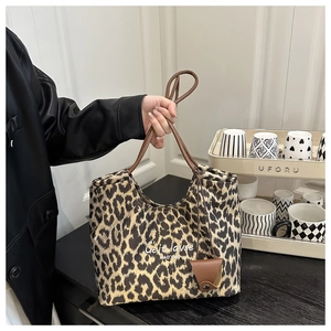Dettaglio della borsa tote leopardata con manici marroni e piccolo ciondolo in pelle