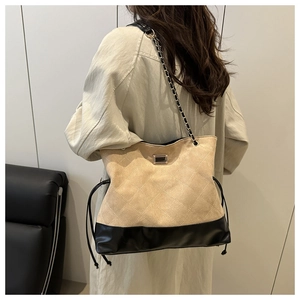 Close-up of quilted beige suede and black leather shoulder bag with gold metal buckle