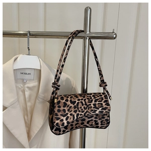 Detailed view of leopard print shoulder bag featuring a saddle-shaped base and knot strap