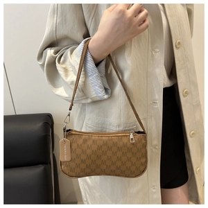 Close-up of vintage tan baguette bag with M-pattern texture and sleek leather strap
