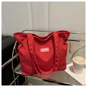 Detail of red nylon tote bag featuring fashion label and side drawstring on metal rack