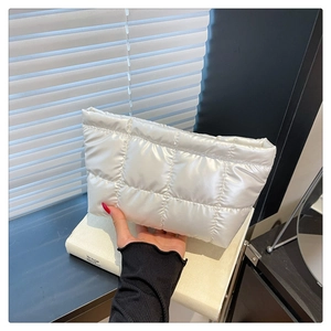 Détail de trousse à maquillage blanche matelassée avec fini nacré et motifs carrés