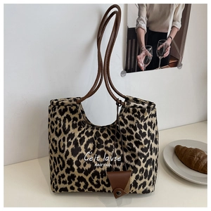 Detail of vintage leopard print tote bag featuring brown straps and artistic text